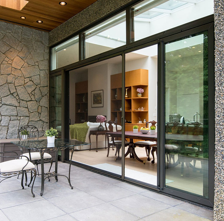 Patio avec murs en pierre et portes vitrées coulissantes, ensemble de salle à manger en fer forgé et étagères de rangement en bois intégrées à l'intérieur