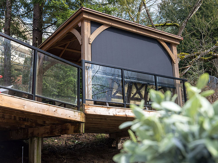 Pergola en bois surélevée avec moustiquaires à guide-câble et garde-corps en verre, mettant en valeur un espace de vie extérieur moderne