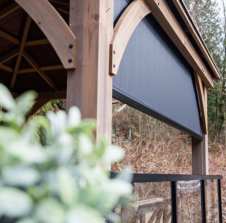 Pergola en bois avec système de moustiquaire à guide-câble foncé, montée sans poteaux d'angle sur fond naturel