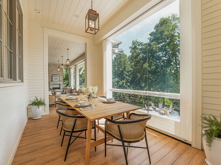 Zone de restauration élégante sur véranda avec table en bois et chaises en rotin surplombant des vues sur un jardin luxuriant