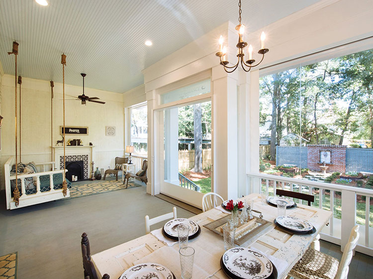 Véranda avec table à manger et balançoire suspendue, présentant une décoration de style ferme et des vues sur l'arrière-cour