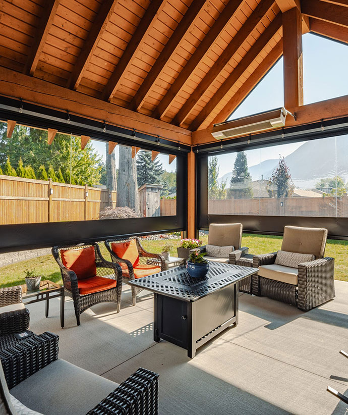 Patio couvert avec écrans rétractables et panneaux en vinyle transparent créant un espace de vie extérieur confortable avec des meubles modernes