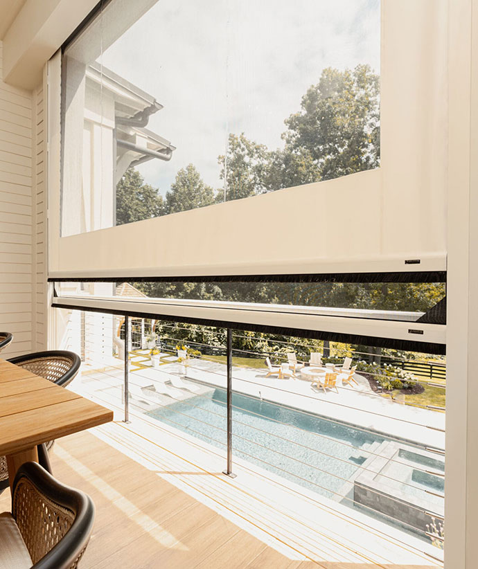 Véranda avec panneaux en vinyle rétractables surplombant une zone de piscine et un espace de divertissement extérieur