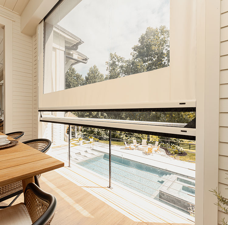 Système d'écran en vinyle partiellement rétracté révélant une vue sur la piscine, présentant une installation de restauration extérieure moderne avec guides de câble