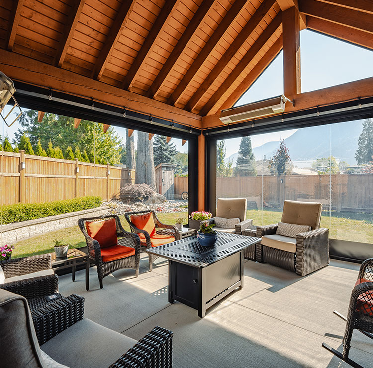 Patio protégé confortable avec sièges d'extérieur, protégé par des panneaux en vinyle transparent avec vues sur les montagnes