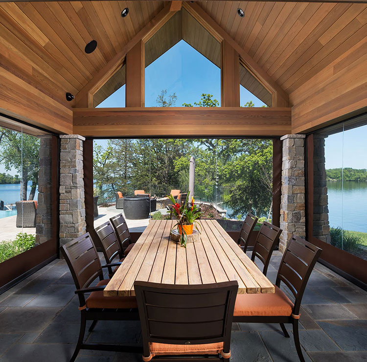 Pavillon de restauration au bord du lac avec écrans en vinyle transparent, table en bois et vues panoramiques sur l'eau