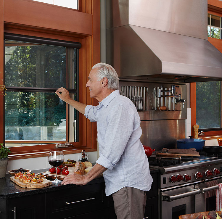 Cuisine moderne avec fenêtres encadrées de bois, cuisinière professionnelle et préparation d'aliments sur des comptoirs noirs