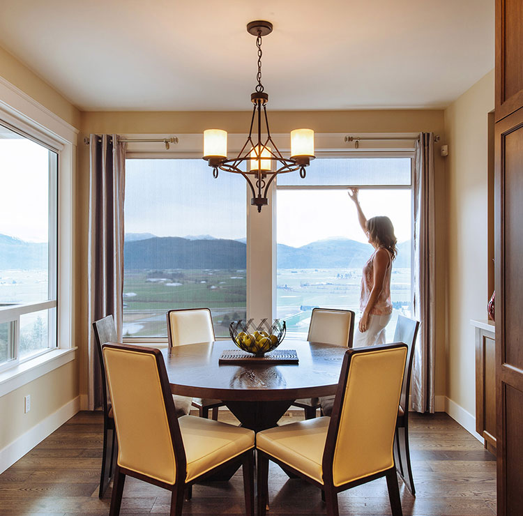 Salle à manger élégante avec vue sur la montagne à travers de grandes fenêtres, avec chaises en cuir crème