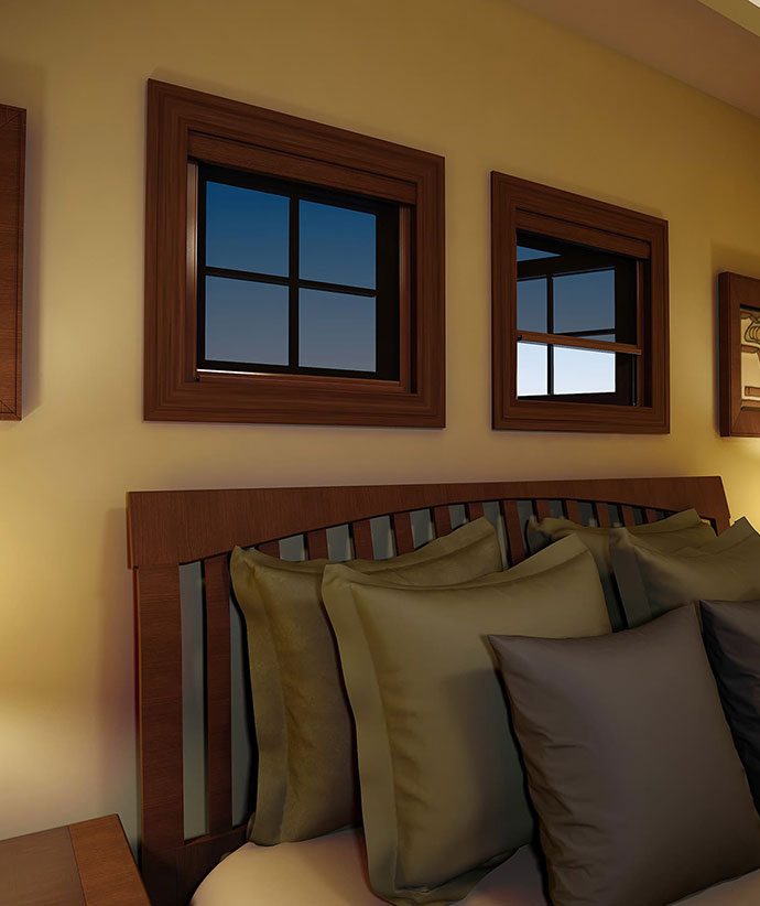 Fenêtres de chambre avec garniture en bois foncé et moustiquaires rétractables, montrant la lumière du soir et un banc de fenêtre garni de coussins