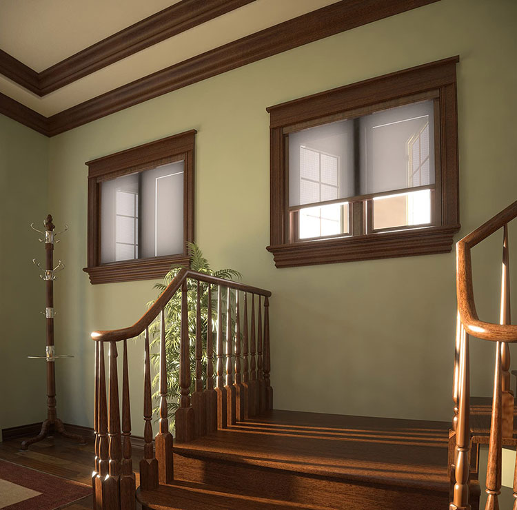 Palier d'escalier élégant avec fenêtres à garniture en bois et moustiquaires rétractables, mettant en valeur la lumière de l'après-midi à travers les balustres